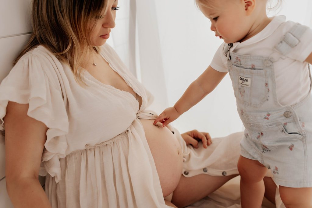 Toddler touching baby bump in Seattle Maternity Studio

